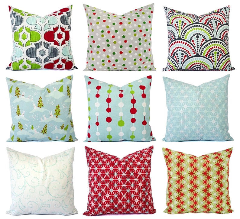 May include: Ten decorative throw pillows with various patterns. The pillows feature a variety of colors, including red, green, blue, and white. The patterns include polka dots, geometric shapes, and snowflakes.