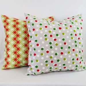 May include: Two decorative throw pillows with a Christmas theme. One pillow has a green and red snowflake pattern, and the other has a gray background with red and green polka dots.