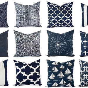 May include: A collection of twelve square throw pillows featuring various navy blue and white patterns, including vertical stripes, geometric lattice designs, anchor motifs, sailboat illustrations, and abstract textures arranged in a grid layout.