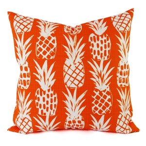 May include: Orange throw pillow with a white pineapple pattern.