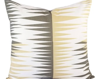 May include: A white pillow with a geometric pattern in shades of gray and beige. The pattern is made up of triangles that point towards the center of the pillow.