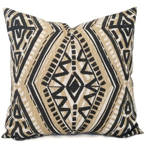 May include: A decorative throw pillow with a geometric pattern in black and beige. The pattern features a diamond shape with smaller triangles and lines within it.