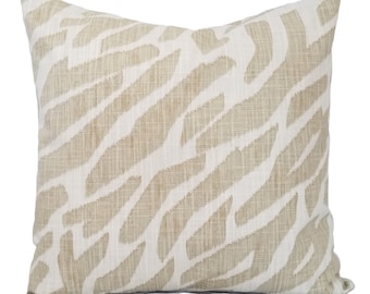 May include: A square throw pillow featuring a textured, woven fabric with a beige and white abstract zebra-like stripe pattern. The design consists of irregular, diagonal brushstroke-style markings in a light tan color against a white background.