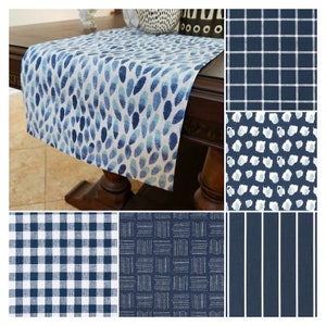 May include: A set of six table runners in various blue and white patterns. The patterns include a blue and white plaid, a blue and white geometric pattern, a blue and white stripe, a blue and white polka dot pattern, and a blue and white abstract pattern.