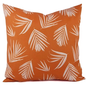 May include: Orange throw pillow with a white palm leaf pattern.