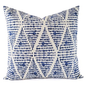 Puede incluir: Una almohada blanca con un patrón geométrico azul. El patrón está formado por pequeños puntos azules dispuestos en forma de diamante.