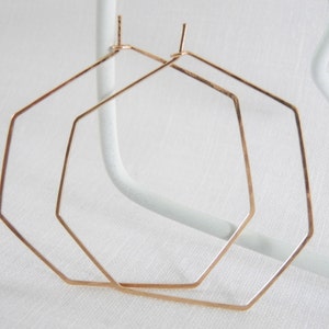 Könnte beinhalten: Ein Paar roségoldene sechseckige Creolen. Die Ohrringe sind schlicht und elegant und eignen sich perfekt als Geschenk für jeden Anlass.