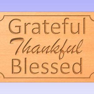 May include: A wooden sign with a light brown stain and a beveled edge. The sign has a decorative border and the words "Grateful Thankful Blessed" are carved into the wood.
