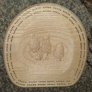 May include: A wooden cribbage board with a carved image of mushrooms and the text "Shroom 12".