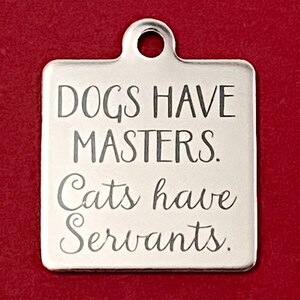May include: Silver square dog tag with the text "Dogs have masters. Cats have servants."