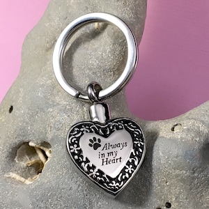 May include: Silver heart-shaped keychain with a paw print and the inscription "Always in my Heart".