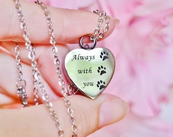 May include: A silver heart-shaped pendant necklace with a chain. The pendant has the words "Always with you" engraved on it and three paw prints.