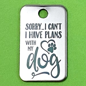 May include: Silver dog tag with the text "Sorry I can't I have plans with my dog" and a paw print heart.