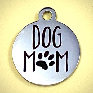 May include: Silver dog tag with the text "DOG MOM" and a black paw print.