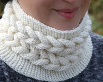 May include: A white knitted neck warmer with a cable knit pattern.
