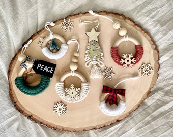 May include: A set of six handmade wooden Christmas ornaments with various designs. The ornaments are decorated with yarn, beads, and fabric. The designs include a snowflake, a Christmas tree, a wreath, and a bow. The ornaments are displayed on a wooden slice.