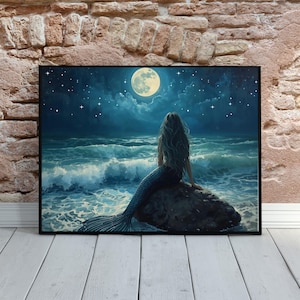 May include: A framed art print depicts a mermaid sitting on a rock, gazing at a full moon over a wavy ocean. The artwork features a dark blue color palette with stars in the night sky. The mermaid has long, flowing hair and a scaled tail.