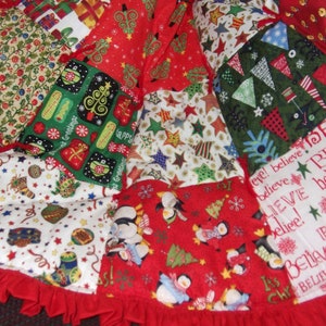 K&ouml;nnte beinhalten: Ein Patchwork-Weihnachtsbaumrock mit rotem R&uuml;schenrand. Der Rock zeigt verschiedene festliche Muster, darunter Pinguine, Weihnachtsb&auml;ume, Geschenke und das Wort "Believe" in wei&szlig;er Schrift auf rotem Hintergrund.