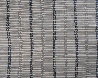 May include: A close-up of a white fabric with a repeating pattern of gray and blue lines. The fabric has a subtle texture.