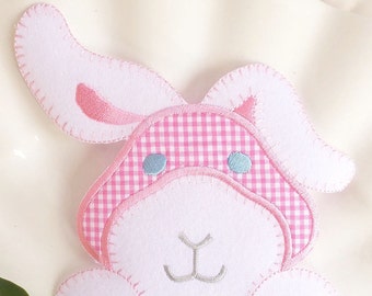 May include: A pink and white felt bunny applique with gingham fabric on the ears and blue embroidered eyes.