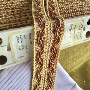 May include: Two spools of gold and red braided trim with a label that reads "&pound;2.49/YD SKU 1079425 ALPHA SEA LOC # 182 709084 conso www.conso.com 21415H VNT31 -314-1-19.1MM 18 YDS te SM 75% POLYESTER 15% CETATE West Warren, MA 01092"