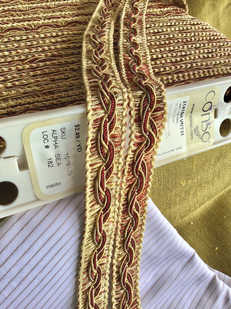 May include: Two spools of gold and red braided trim with a label that reads "&pound;2.49/YD SKU 1079425 ALPHA SEA LOC # 182 709084 conso www.conso.com 21415H VNT31 -314-1-19.1MM 18 YDS te SM 75% POLYESTER 15% CETATE West Warren, MA 01092"
