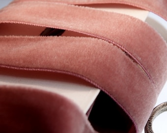 Puede incluir: Primer plano de una cinta de terciopelo rosa suave. La cinta está doblada en varias capas, mostrando la textura de la tela.