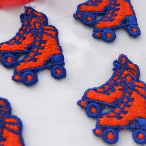 May include: Five orange and blue embroidered roller skate patches. The patches are on a white background.