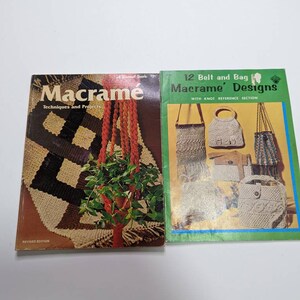May include: Two vintage macrame books. The book on the left is titled "Macrame Techniques and Projects" and features a photo of a macrame plant hanger. The book on the right is titled "12 Belt and Bag Macrame Designs" and features a photo of various macrame bags.