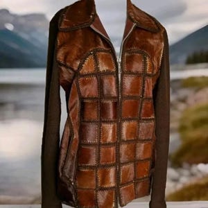 May include: A brown leather jacket with a patchwork design. The jacket has a zipper closure and long sleeves.