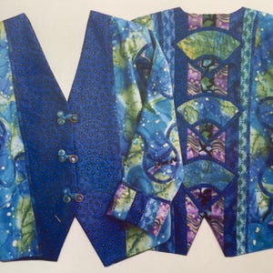 May include: Two blue and green patterned fabric pieces, one with a button closure and the other with a more intricate design. The fabric pieces are likely for a clothing project.