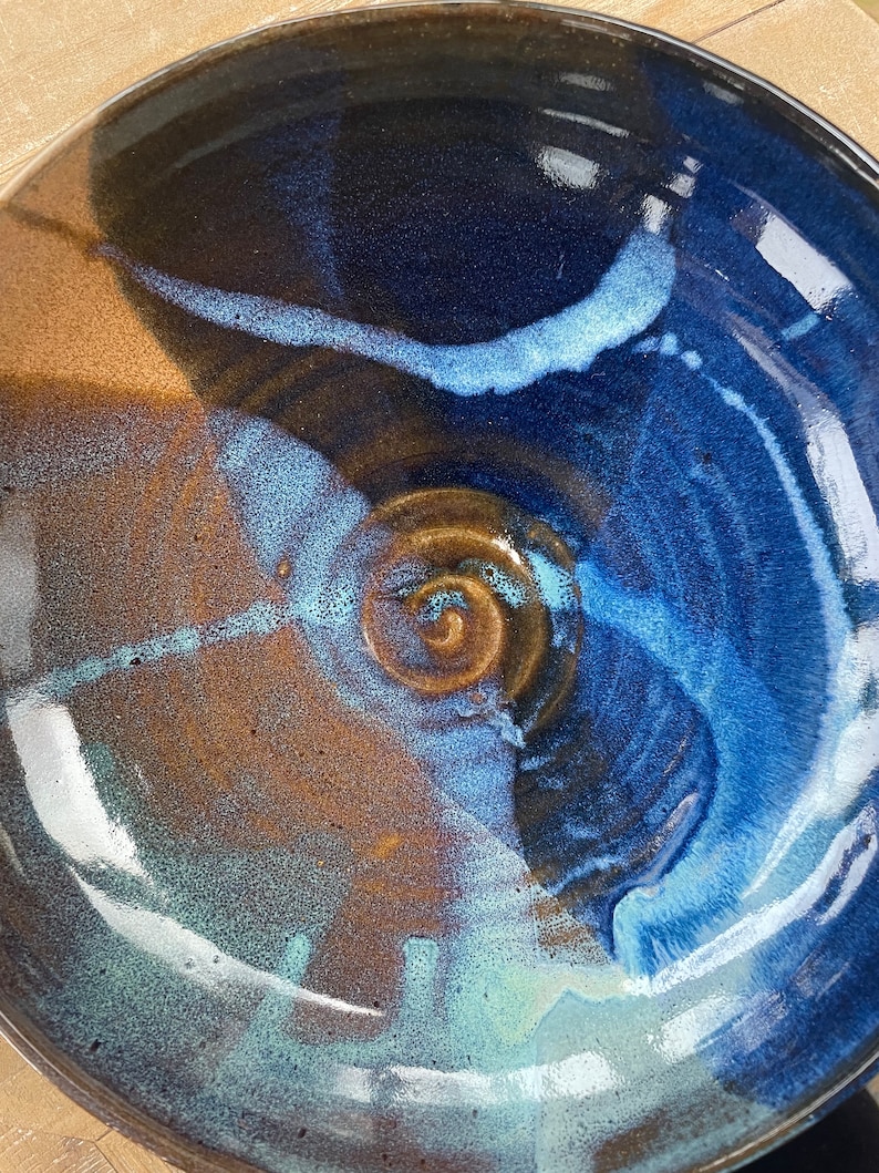 May include: A large ceramic bowl with a blue, brown, and white glaze. The bowl has a swirling pattern and a glossy finish.