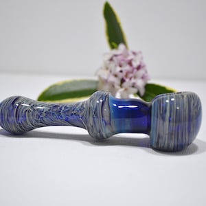May include: A blue and white glass pipe with a swirl design. The pipe is made of glass and has a round bowl.