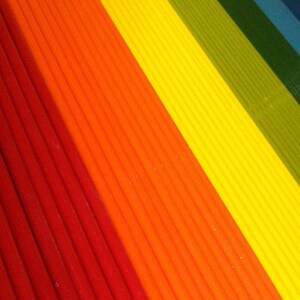 May include: A close-up of a rainbow-colored striped fabric. The fabric is made of thin, vertical stripes in red, orange, yellow, green, blue, and purple.