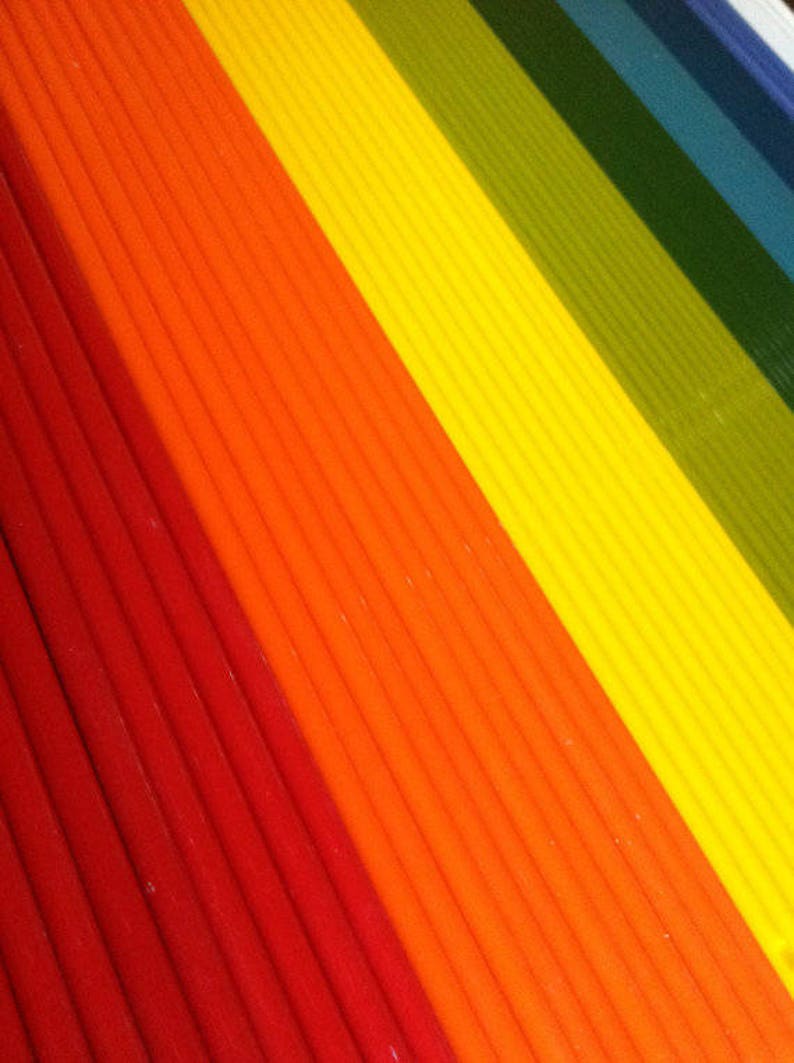 May include: A close-up of a rainbow-colored striped fabric. The fabric is made of thin, vertical stripes in red, orange, yellow, green, blue, and purple.