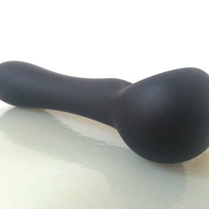 May include: A black, smooth, curved spoon-shaped object made of silicone.