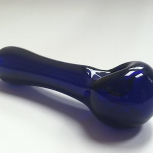 May include: A cobalt blue glass pipe with a rounded bowl and a long, slender stem.