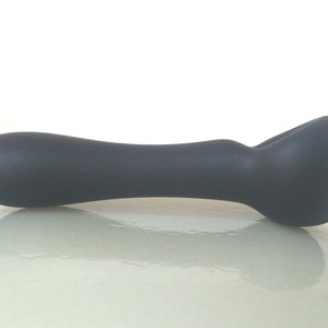 May include: A dark gray glass pipe with a rounded bowl and a long, curved stem.