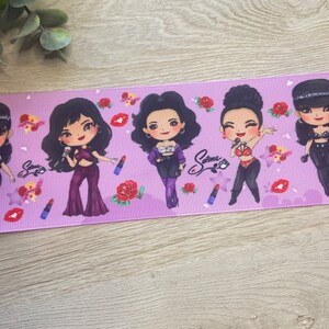 May include: Purple ribbon with a repeating pattern of cartoon figures of women with red roses and lipstick. The text "Selena" is printed on the ribbon.