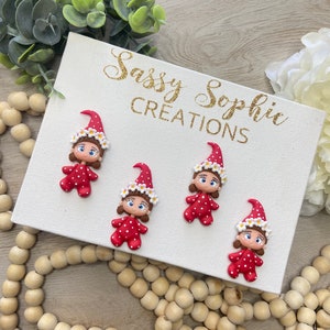 May include: Four handmade gnome figurines with red polka-dot dresses and matching hats with white daisy accents are displayed on a white canvas. The canvas has the text "Sassy Sophie CREATIONS" in gold glitter.