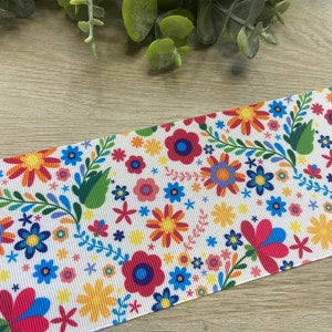 Puede incluir: Cinta blanca con un patr&oacute;n floral colorido. El patr&oacute;n presenta flores rojas, amarillas, azules, verdes y rosas sobre un fondo blanco.