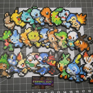 May include: A collection of 30 colorful pixel art characters, each depicting a different Pokemon character. The characters are made of small plastic beads and are arranged in three rows. The characters are all different sizes and shapes, and they are all facing forward. The characters are all on a black background.