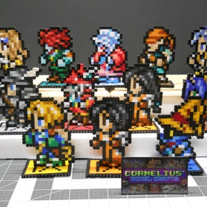 May include: A collection of pixel art figures, each crafted from colorful beads. The figures, in various poses, stand on individual bases and are arranged on a two-tiered display. The figures are in the style of a video game.