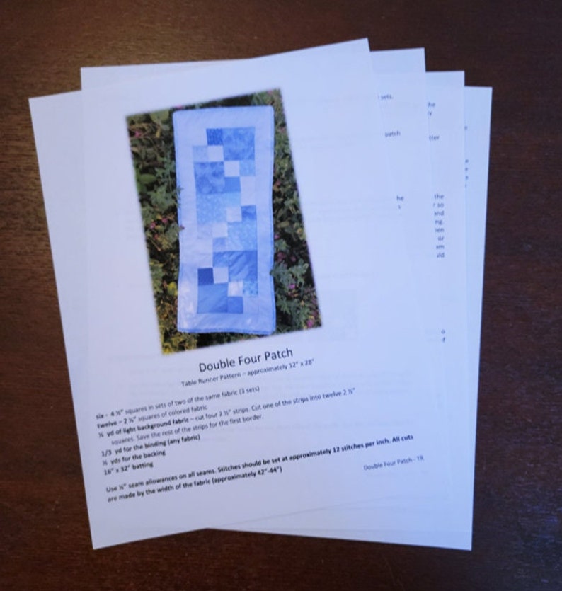 May include: A quilting pattern for a double four patch table runner. The pattern includes instructions for cutting fabric, sewing seams, and finishing the runner. The finished runner will be approximately 81 cm by 71 cm.