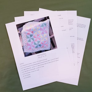 May include: A set of instructions for making a quilt called "Pinwheel". The instructions include a list of supplies, such as fabric, batting, and backing. The quilt is made with a variety of colors, including pink, green, yellow, and blue.