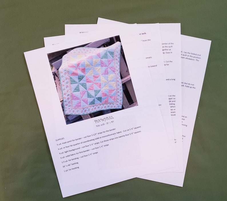 May include: A set of instructions for making a quilt called "Pinwheel". The instructions include a list of supplies, such as fabric, batting, and backing. The quilt is made with a variety of colors, including pink, green, yellow, and blue.