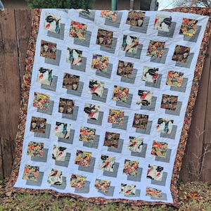 May include: A white quilt with a geometric pattern of squares. Each square features a different fabric with a floral or geometric design. The quilt has a brown border.