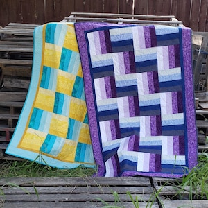 May include: Two quilted blankets, one with a blue and yellow geometric pattern and the other with a purple and blue geometric pattern.