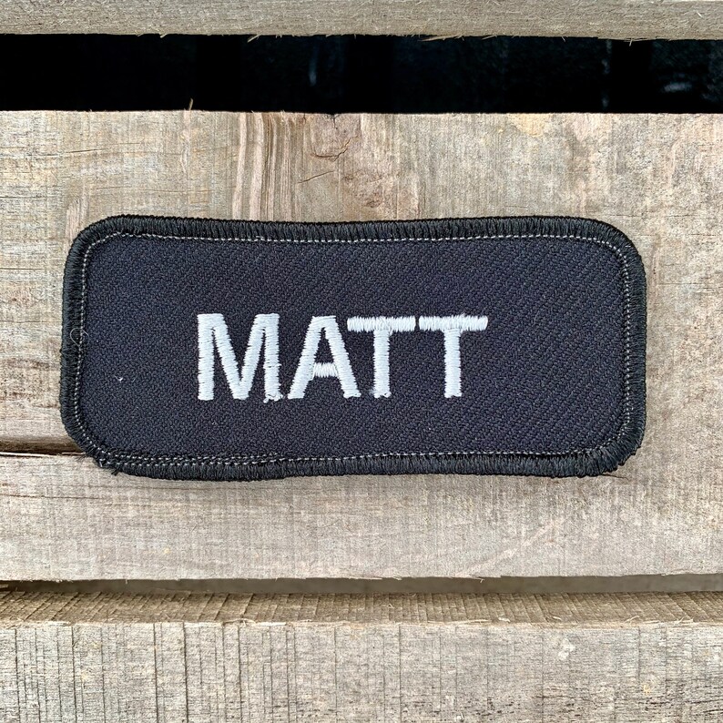 Matt A black work shirt patch that says Matt in white print