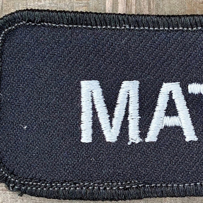 Matt A black work shirt patch that says Matt in white print
